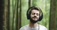 man listening to headphones in a forest