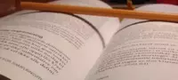 An open book with a wooden stick lying across the pages