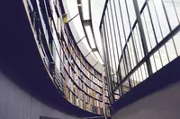 looking up towards bookshelves with books in a modern library with a glass roof