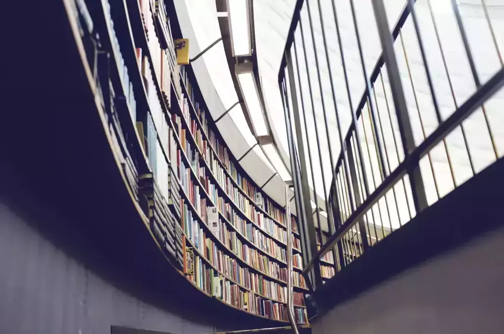 looking up towards bookshelves with books in a modern library with a glass roof