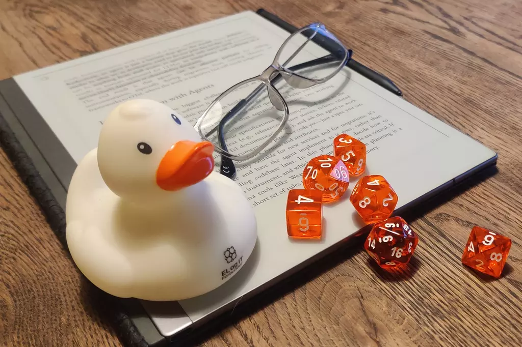 The tools of the trade. A book, glasses, dice and a rubber-duck.